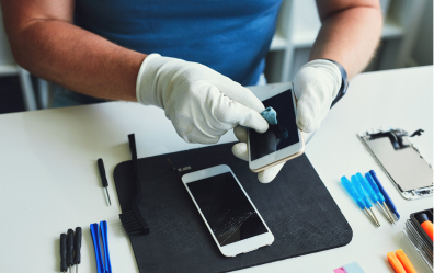 Technicien réparant un smartphone avec des outils de précision, expert en réparation mobile.